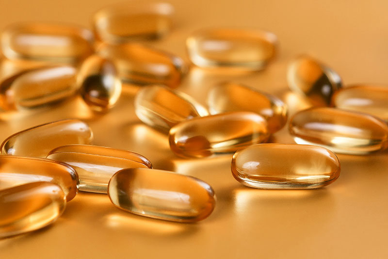 MAny clear golden gel capsules on a golden table